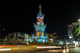 Colourfully illuminated Clock Tower at night with light trails of vehicles