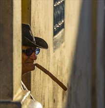 An elderly Cuban sitting on a doorstep in the evening light