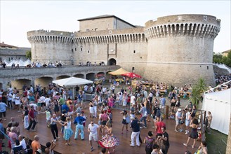 People dancing in the festival grounds in front of Fortress Rocca Roveresca