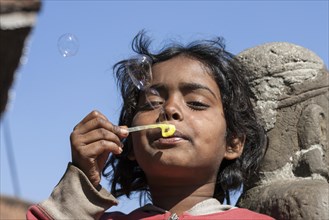 Nepalese girl making soap bubbles