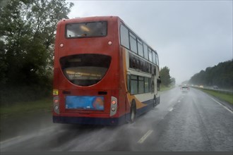 Red bus in the rain on the highway