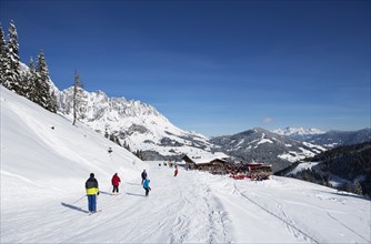 Skiers on ski slope in front of mountain scenery