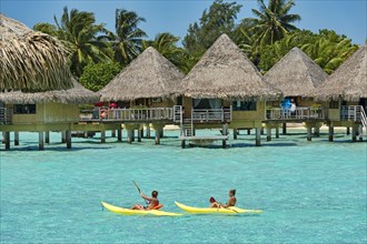 Paddlers in front of overwater bungalows