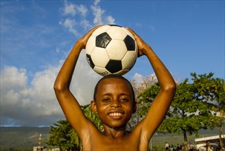 Smiling boy holding a football on his head