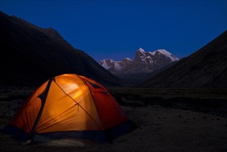 Illuminated tent at Laguna Jahuacocha lake at dusk