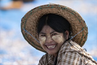 Local woman with a straw hat and Thanaka paste in her face
