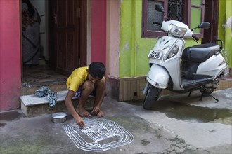 Boy painting a traditional Rangoli