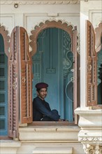 Museum guard sitting by the window in the City Palace of the Maharaja