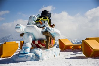 Snowman with sunglasses and a top hat sitting in a deck chair