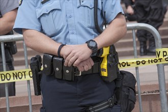 Policeman carries a gun on his right and a taser on his left