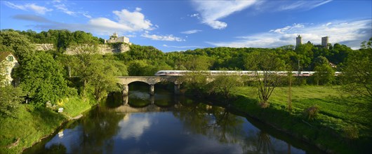 Ruins of Rudelsburg Castle and Burg Saaleck Castle on the Saale River with an ICE train crossing a railway bridge