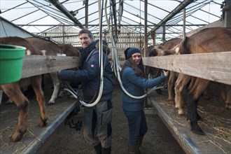 Young farmer and his daughter milking goats