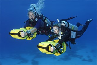 Divers with diver propulsion vehicles exploring a coral reef