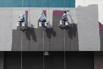 Decorators painting the facade of a high-rise building