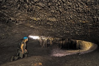 Tourist in a subterranean lava tube created by an eruption of the Piton de la Fournaise volcano