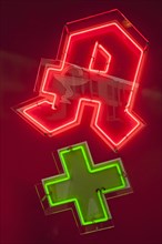 Neon sign of a pharmacy with a green cross
