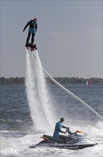 Flyboarder on the water jet of a jet ski