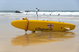 A yellow surfboard of the lifeguards is lying on the beach