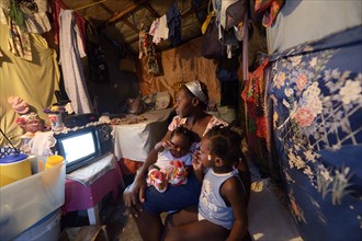 Woman with two children watching television in a shack