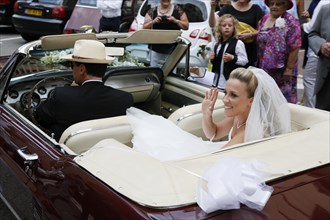 Bride in open Ford Mustang greeting her wedding guests
