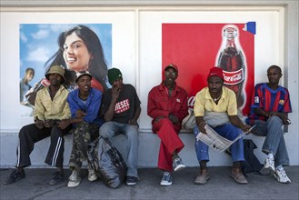 Namibian men sitting in front of advertising posters