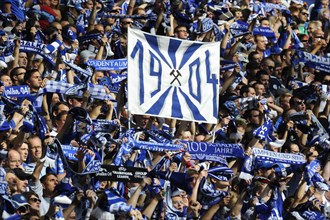 Schalke fans on the north stand holding up scarves and a banner ""1904""