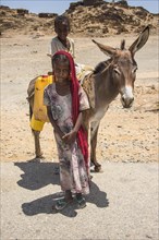 Girl and boy with a donkey on the way to a waterhole