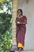 Smiling woman leaning against a pillar in Alappuzha