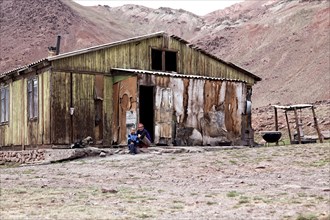 People sitting outside a delapidated hut