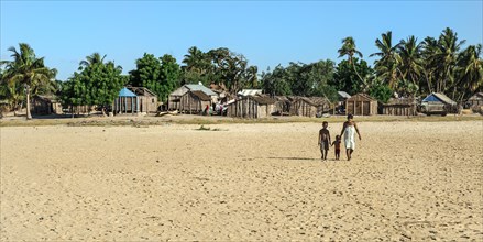 Malagasy woman and her two children walking on the beach