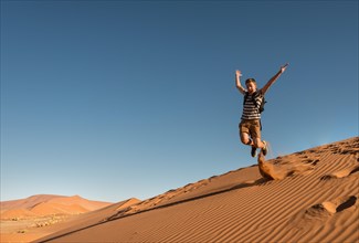 Teenager jumping and running down a dune