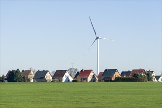 Wind turbine by village with houses in an agricultural landscape