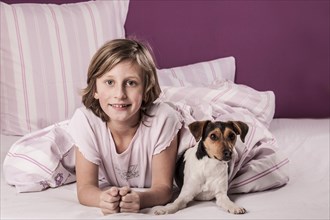 Girl lying in bed with a Danish Swedish Farmdog