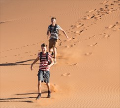 Two teens running down a dune