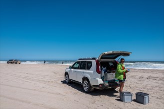 Tourist standing next to an SUV on the Namibian coast near Swakopmund