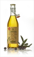 A bottle of olive oil with black olives and olive leaves (Olea europaea) as decoration