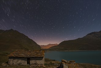 Night sky above Mont Cenis lake and a hut
