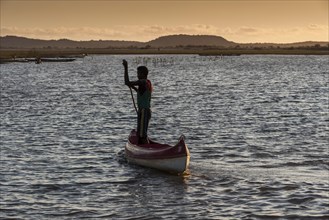 Fisherman punting a pirogue on the Manambolo in the morning light