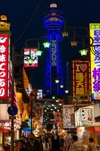Many colorful neon signs in a pedestrian zone with shops and restaurants