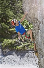 Sport climber wearing a helmet climbing a rock face