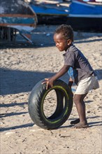 Malagasy child playing with a used tire