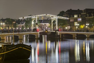 Magere Brug bridge over the river Amstel illuminated at night