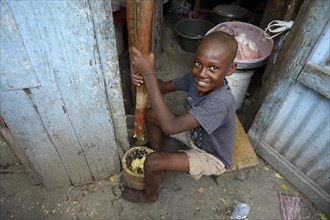 Boy pounding corn into flour in a mortar