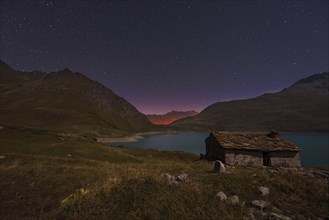 Night sky above Mont Cenis lake and a hut