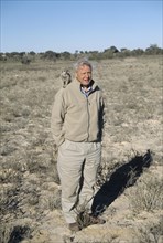 Sir David Attenborough with meerkat on shoulder for BBC series The Life of Mammals
