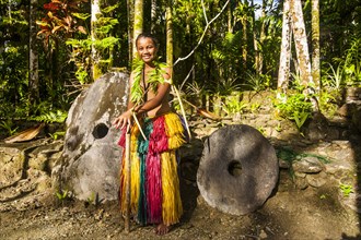 Traditionally dressed girl standing in front of stone money