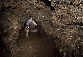 Tourist standing in a subterranean lava tube created by an eruption of the Piton de la Fournaise volcano