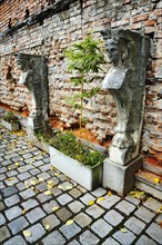 Stone sculptures and bamboo in front of a brick wall