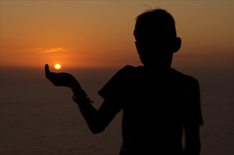 Silhouette of a child against the sunset sky