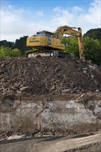 Excavator standing on a large rubble heap